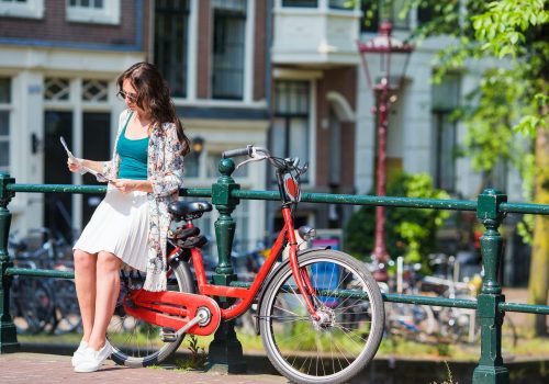 Happy young woman with a city map on bike in european city